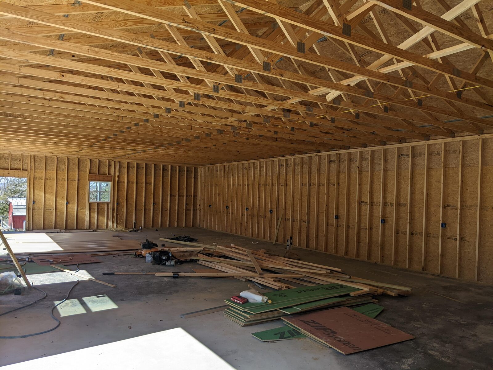 Interior of a building under construction showing wood roof trusses and framed stud walls