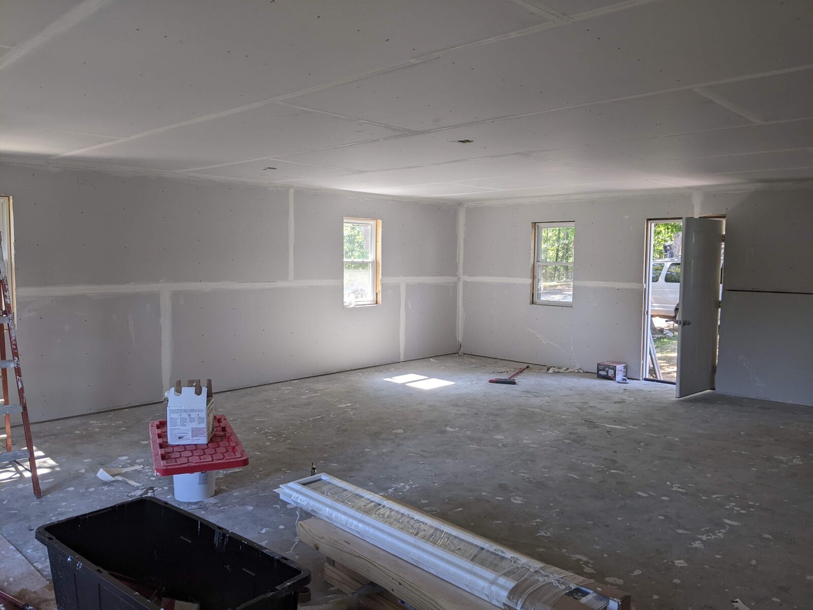 Open interior room with freshly hung drywall and natural light from new windows