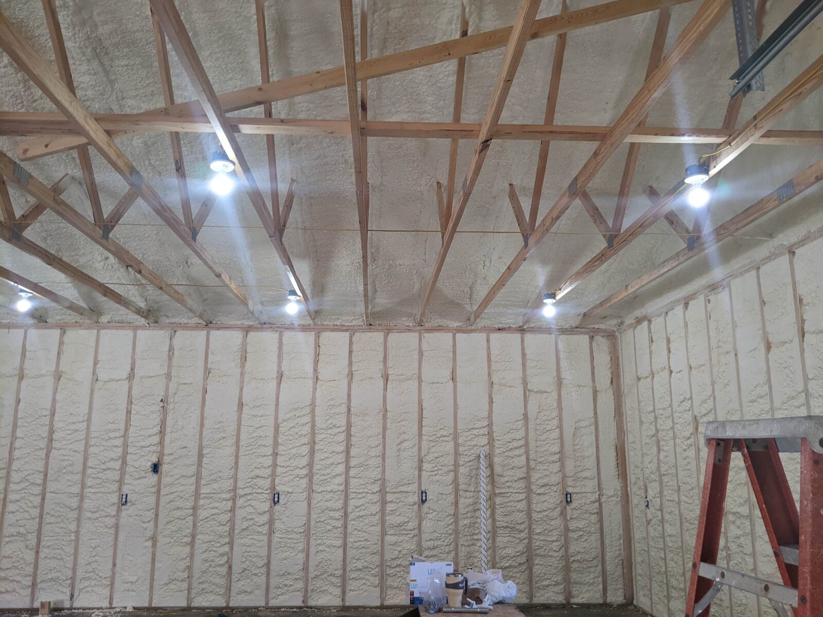 Spray foam insulation applied to walls and roof trusses inside a new building