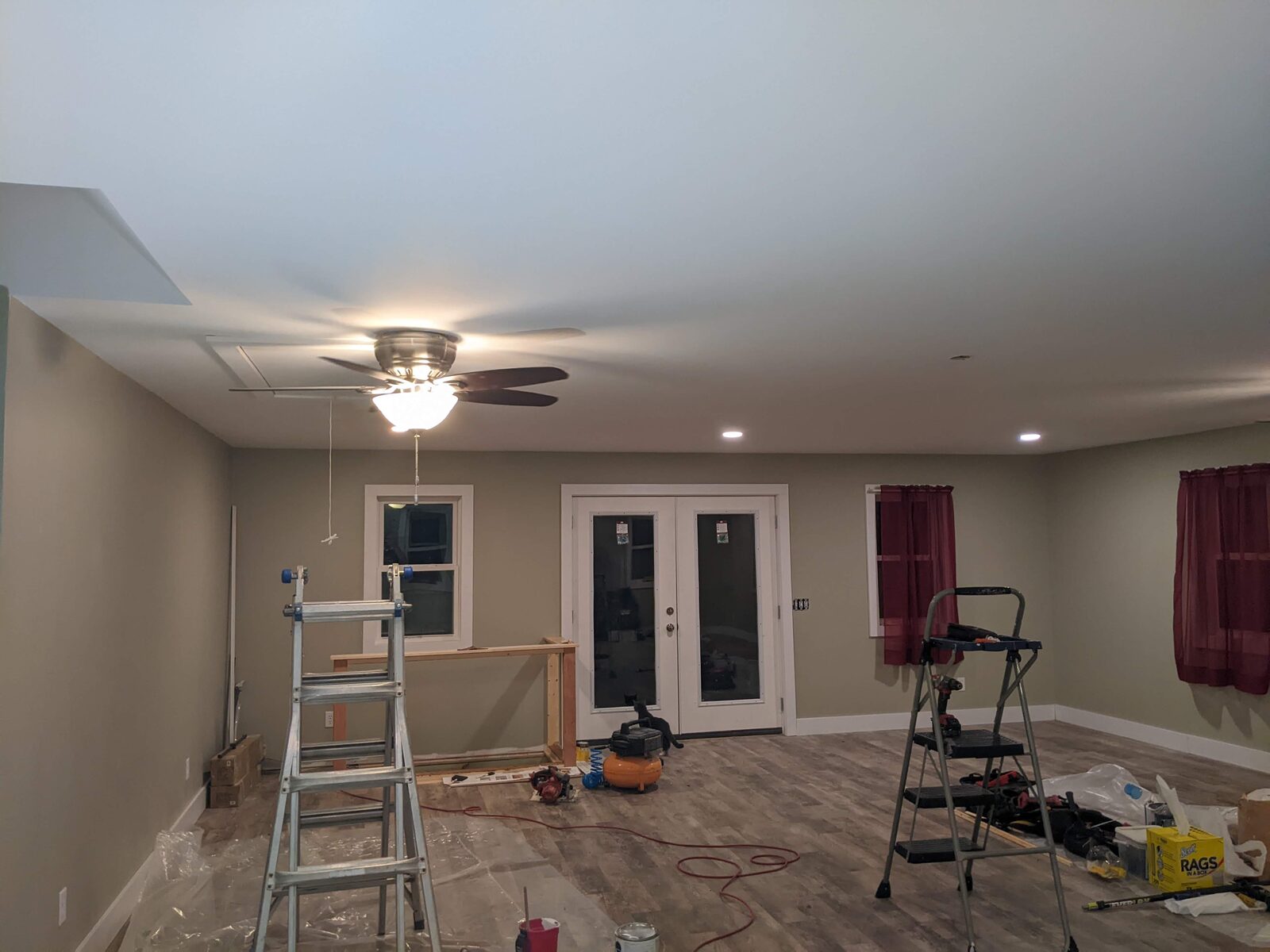 Nearly finished living room with painted walls, ceiling fan, French doors and new flooring