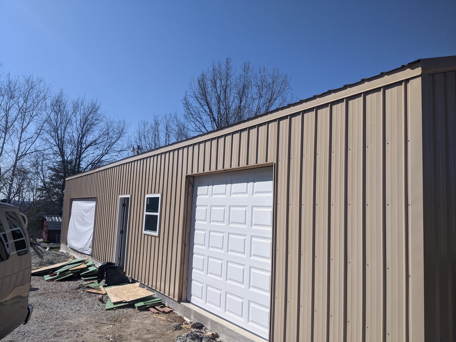 Completed exterior of a tan metal garage building with white overhead door