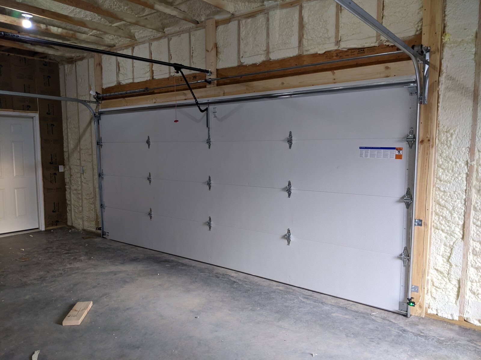 Interior of finished garage with insulated overhead door and spray foam walls