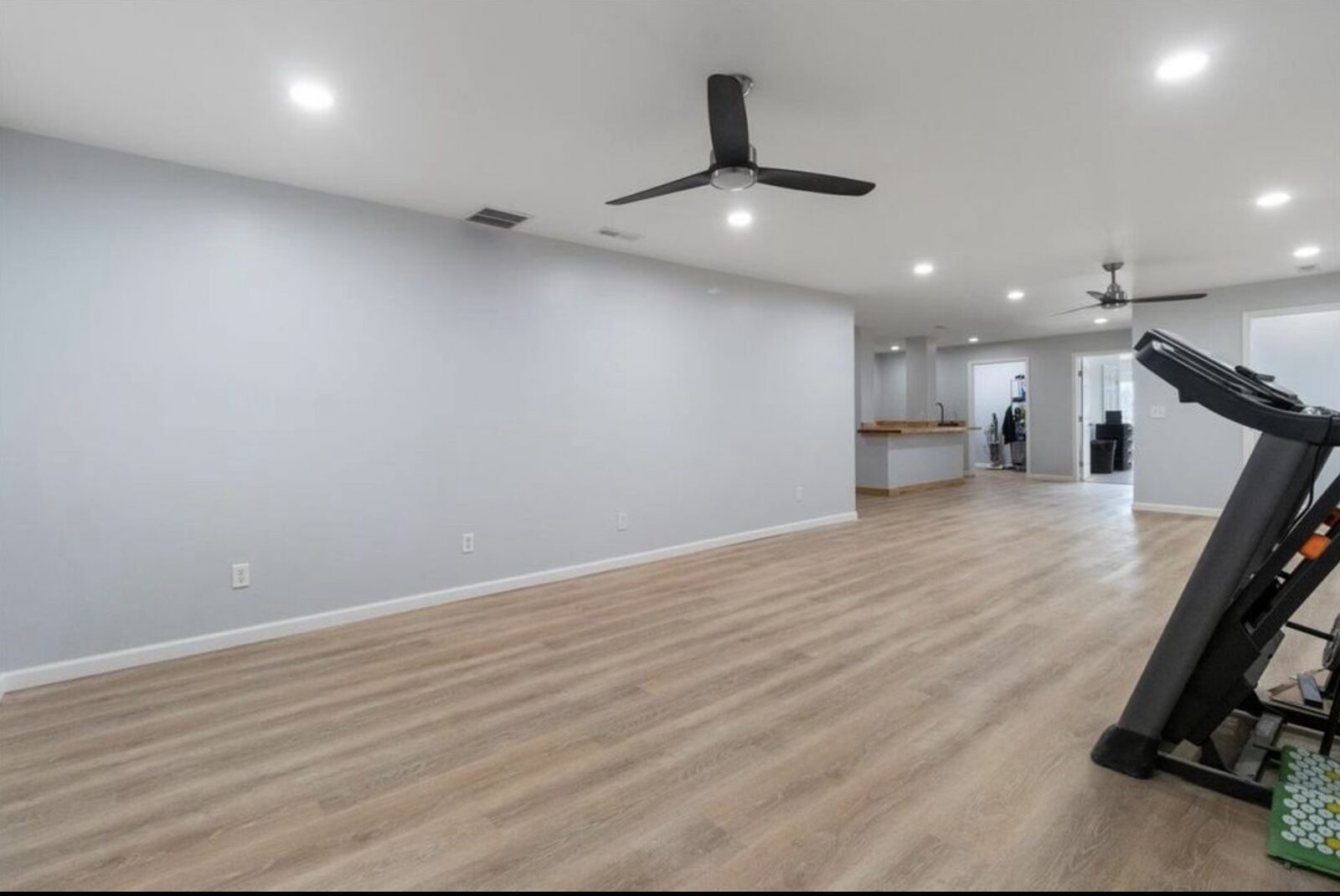 Large open finished living area with vinyl plank floors and modern ceiling fan