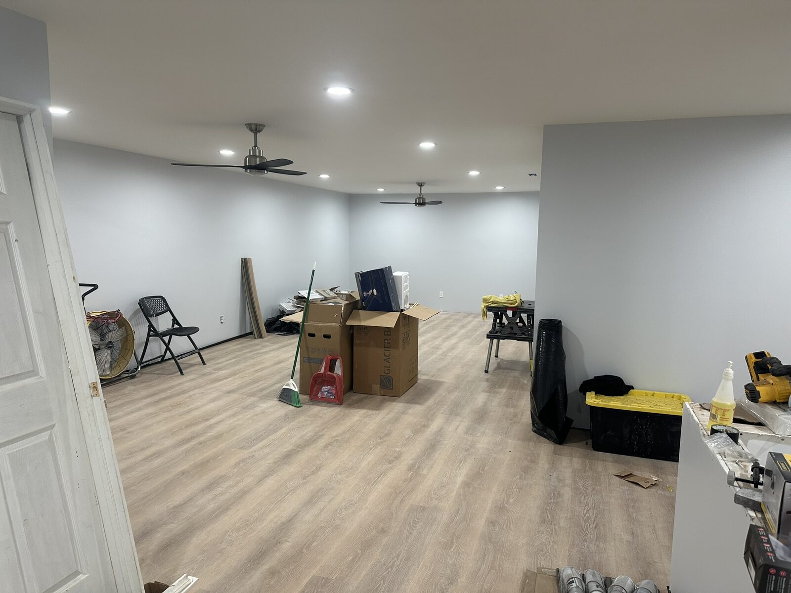 Finished living room with light vinyl plank floors and recessed lighting
