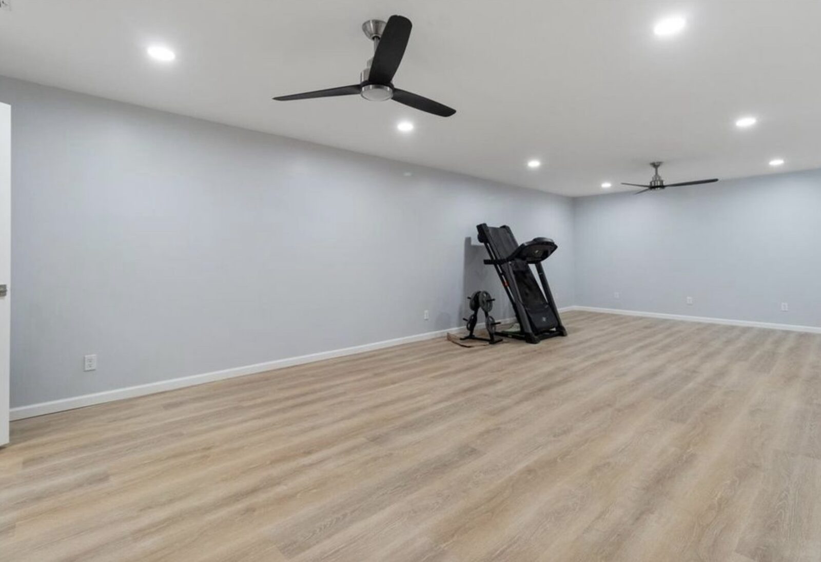 Spacious finished bonus room with two modern ceiling fans and vinyl plank flooring