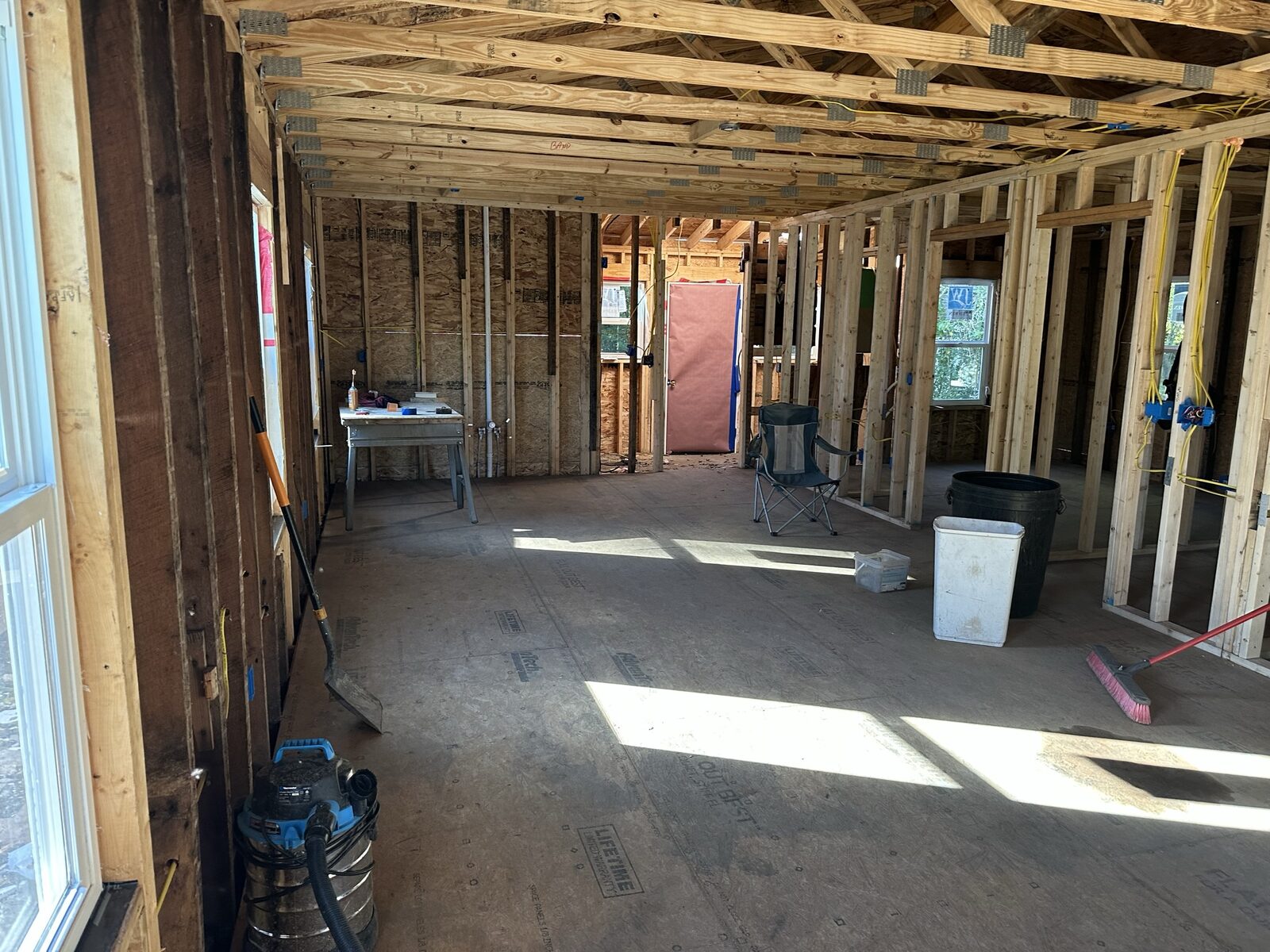 Interior of building under construction with open framed walls, joists and plywood subfloor