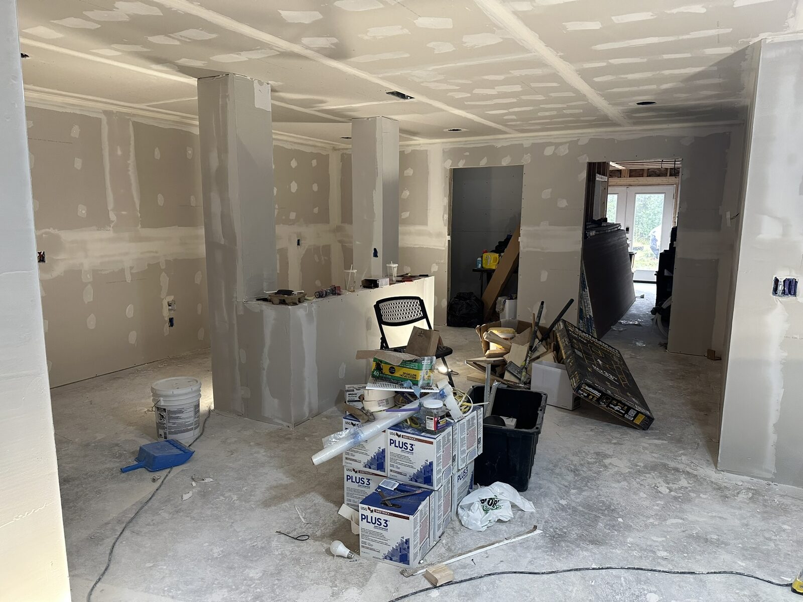 Interior with drywall hung and taping in progress, materials staged on the floor